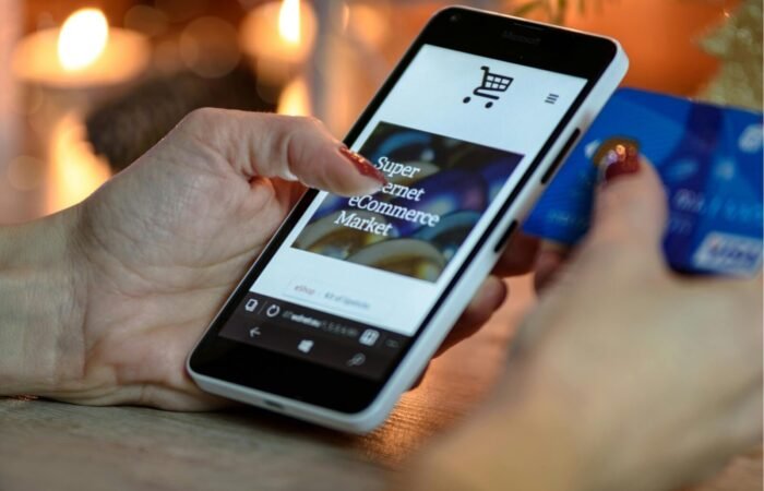 Seseorang sedang nyaman berbelanja online menggunakan smartphone dengan tampilan website e-commerce yang responsif dan rapi.