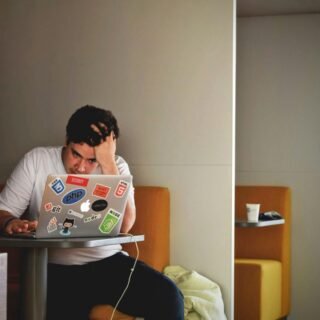 Ilustrasi seorang pengusaha UMKM yang stres mengatur kode website sendiri dibandingkan dengan bekerja sama dengan agensi profesional.
